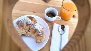 A heart-shaped tray with a croissant, a cup of coffee, and a glass of orange juice on a wooden table. - The Calypso Mansion (Salerno)