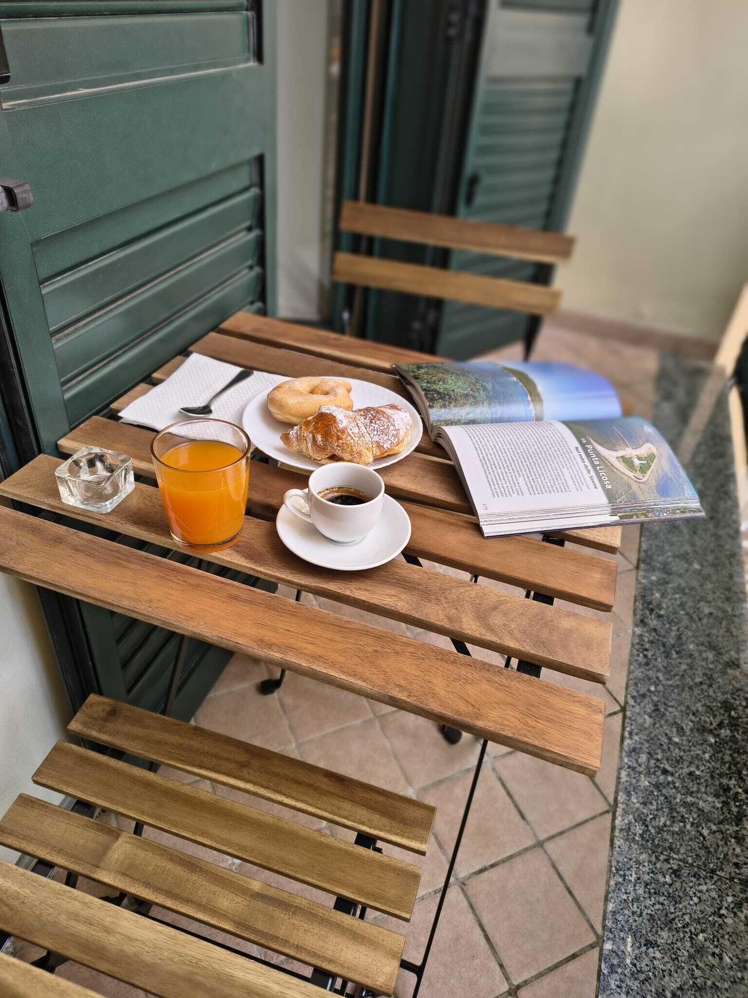 Ein Holztisch mit einem Croissant, einer Tasse Kaffee und einem Glas Orangensaft.
