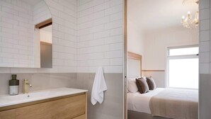 Une salle de bain moderne avec un mur recouvert de carreaux blancs, un meuble-lavabo en bois et un grand miroir.