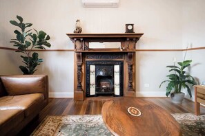 A living room with a fireplace, leather sofa, and potted plants.