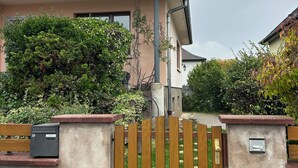 Una casa residencial con techo inclinado, una reja de madera y un muro de concreto.