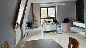 Una sala de estar moderna con una mesa de comedor, sofás y un amplio ventanal.