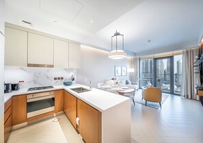 A modern kitchen with a central island, built-in oven, and marble backsplash.