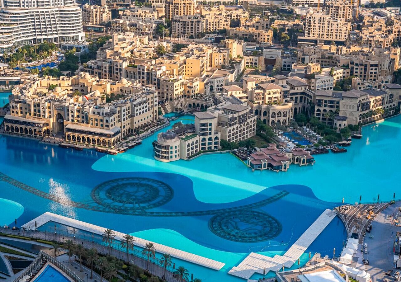 A large, modern hotel with a central swimming pool, surrounded by dense urban buildings.