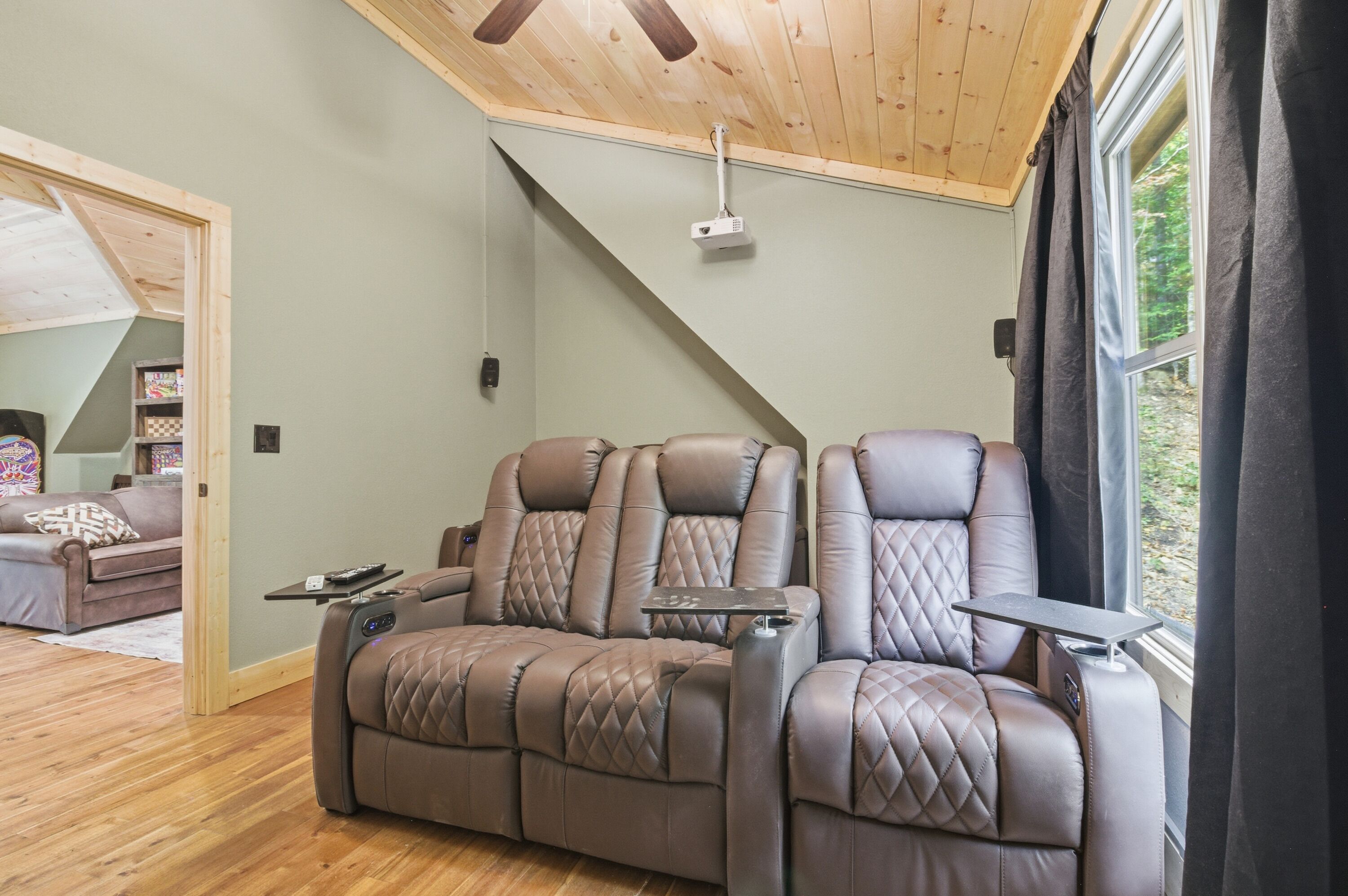 A modern living room with a brown leather sofa, a wooden ceiling, and a large window.