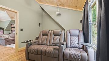 A modern living room with a brown leather sofa, a wooden ceiling, and a large window.