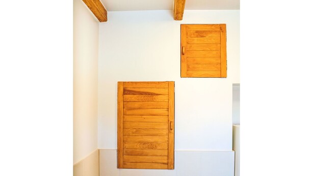 Une salle de bain avec des murs recouverts de carreaux blancs, des poutres en bois et deux panneaux en bois sur le mur.