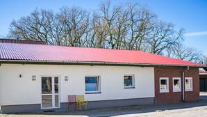 Il s’agit d’un bâtiment d’un seul étage, doté d’un toit rouge, d’une façade blanche et d’un petit porche avec deux chaises.