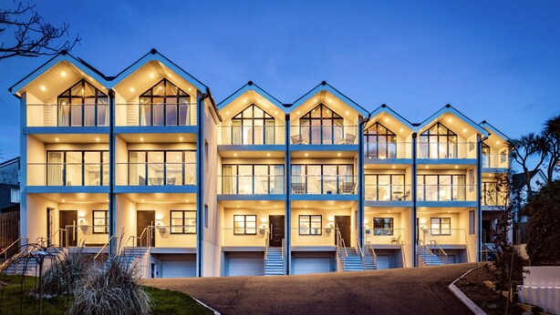 A multi-story residential building with a symmetrical design, featuring multiple balconies and large windows.
