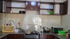 A kitchen with dark wooden cabinets, a stove, and various kitchen utensils.