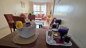 A dining area with a wooden table, a woven basket, and a tray with beverages and condiments.