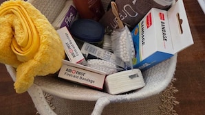 A basket filled with various personal care items and a plush toy on a wooden table.