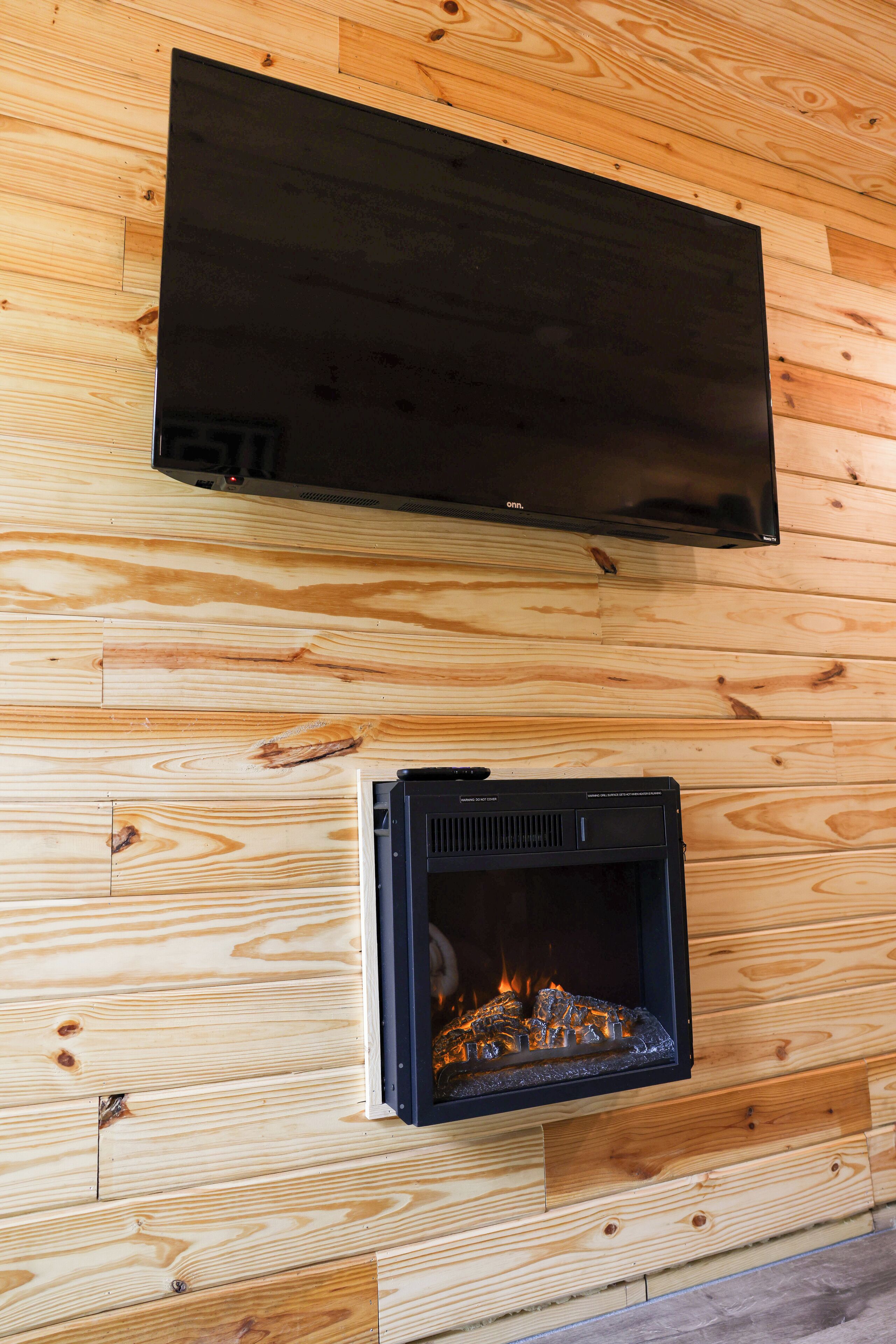 A flat-screen TV mounted on a wooden wall above a fireplace.