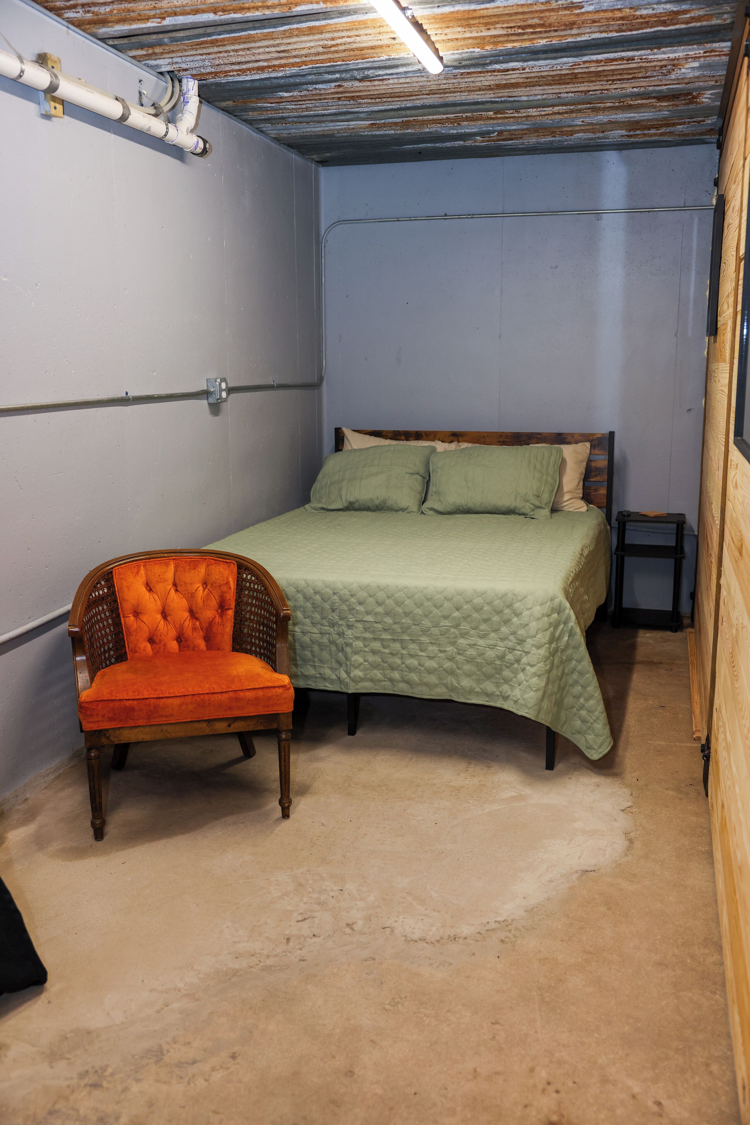 Une chambre à coucher avec un lit, une chaise et un petit tabouret.
