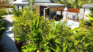 Ein Haus mit Schwimmbad, umgeben von üppiger Vegetation und blauem Himmel.