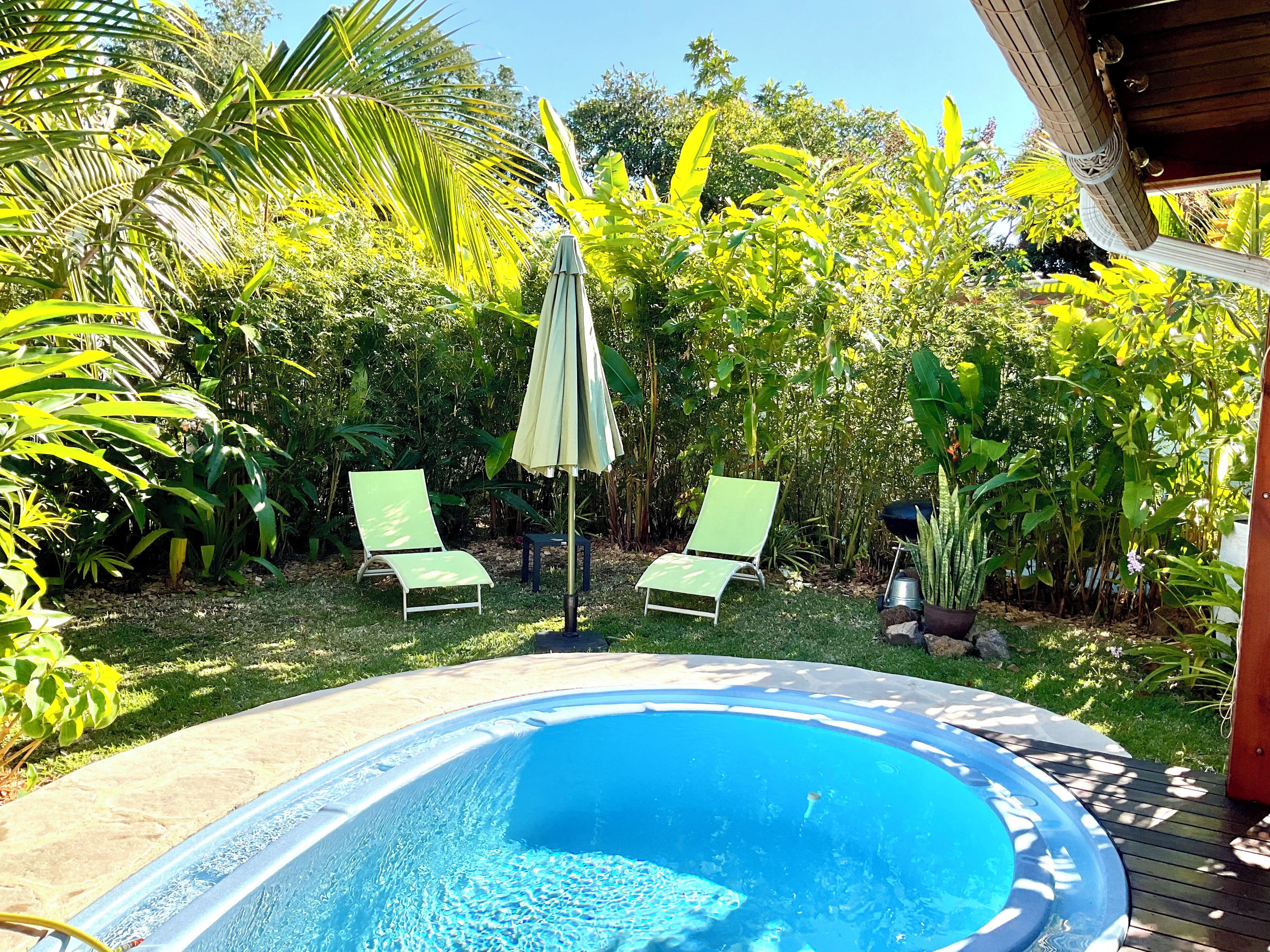 Piscina ao ar livre com duas espreguiçadeiras verdes e um guarda-sol.