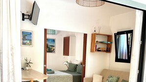 Ein gemütlicher, kompakter Wohnbereich mit Bett, Sofa, Esstisch und einem an der Wand befestigten Fernseher.