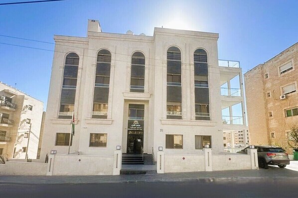 A building with a symmetrical facade, large arched windows, and a central entrance with steps.