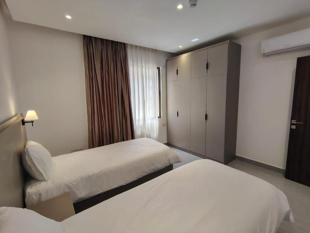 Quarto de hotel com duas camas de solteiro, um guarda-roupa e um aparelho de ar condicionado.