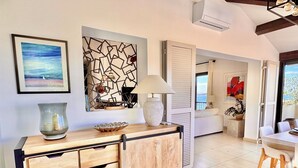 Un salon moderne avec un meuble en bois, une grande peinture abstraite et une vue sur l’extérieur.