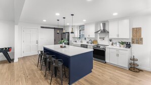 Une cuisine moderne dotée d’un îlot central, de meubles blancs et d’une hotte de cuisinière en acier inoxydable.