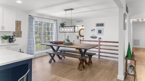 Une cuisine moderne avec une table et un banc en bois, des armoires blanches et une grande fenêtre.