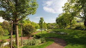 Un jardin bien entretenu, avec un chemin de gravier, des haies soigneusement taillées et une variété d’arbres.