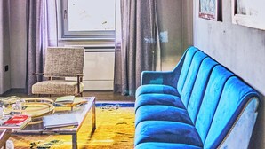 A room with a blue sofa, a chair, a table with books and a glass, a window with curtains, and a lamp. - Godiluva, wine villa (Toscana)