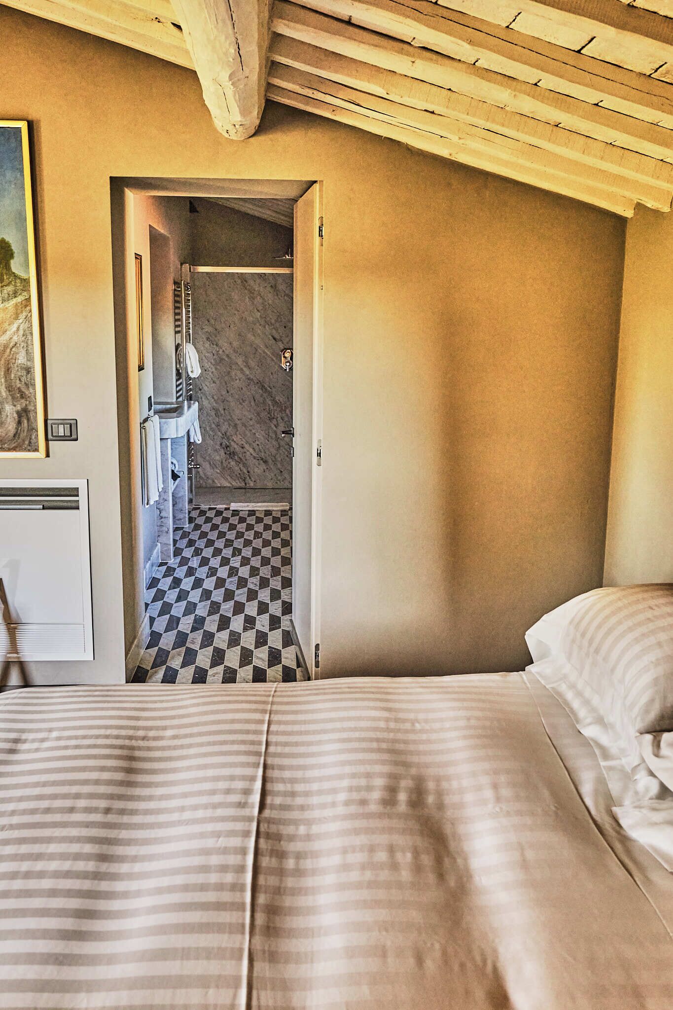 Ein Schlafzimmer mit Schachbrettfußboden, einem Bett mit gestreifter Bettwäsche und einer Holzzieldecke.