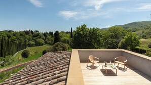 A terrace with a view of a vineyard, two wooden chairs, and a table with a vase and book. - Godiluva, wine villa (Toscana)