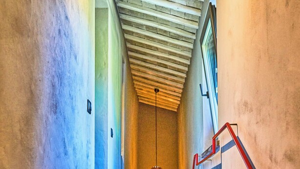 A staircase with a wooden ceiling and a red handrail leading to a landing. - Godiluva, wine villa (Toscana)