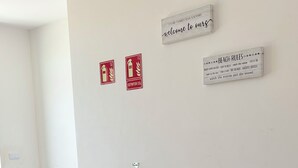 Huoneessa on kaksi ruskeaa nahkaista nojatuolia, pieni pyöreä pöytä, jonka päällä on kasvi, ja marmorilattia. Seinällä on kaksi punaista kylttiä, toisessa on palosammuttimen symboli ja toisessa ohjeet rannalla käyttäytymiseen.
