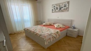 Una camera da letto con un letto, un comodino, una lampada e una finestra con tende.