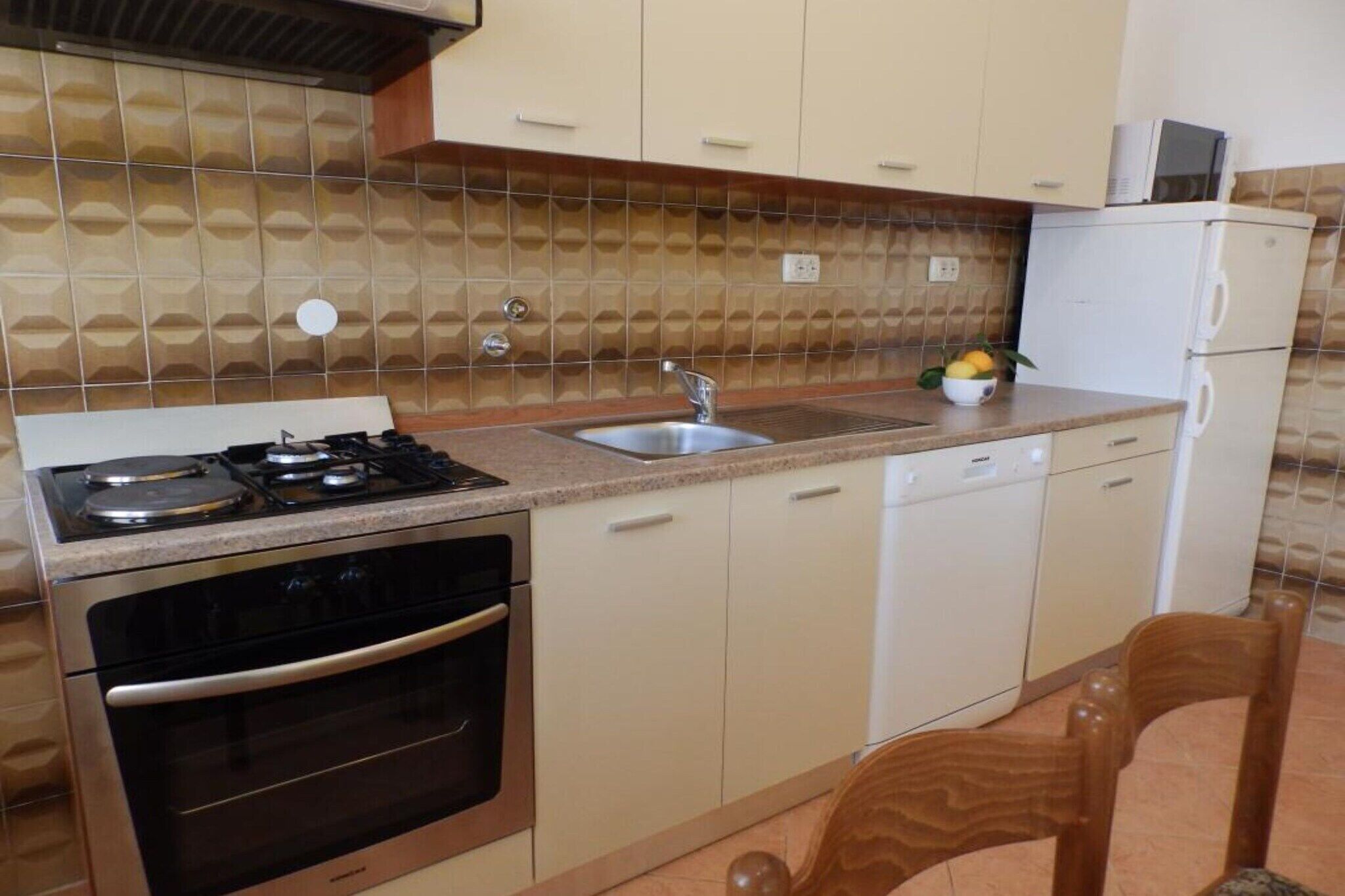 A compact kitchen with a gas stove, oven, sink, and dishwasher.