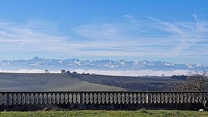 A rural landscape with a wooden fence, fields, and distant snow-capped mountains under a clear sky. - Gite Casa Tutel (Esperce)