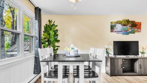 A dining area with a table and chairs, a TV, and a cabinet. - TruStay in Central CT (Manchester)