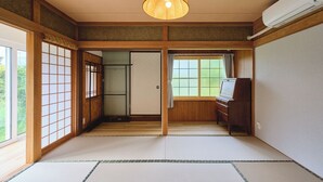 Ein traditioneller japanischer Raum mit Tatami-Böden, Schiebetüren, einem Shoji-Bildschirm, einer hängenden Papierlaterne und einer Klimaanlage.