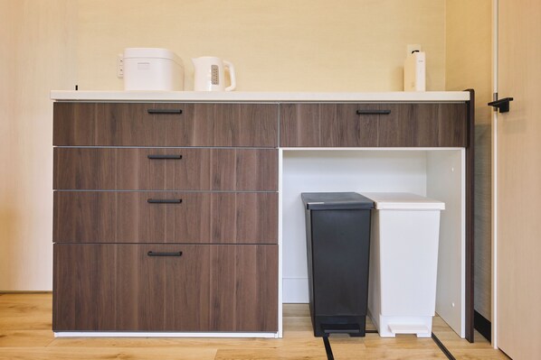 A kitchenette with a brown cabinet, a white refrigerator, and a black trash bin.
