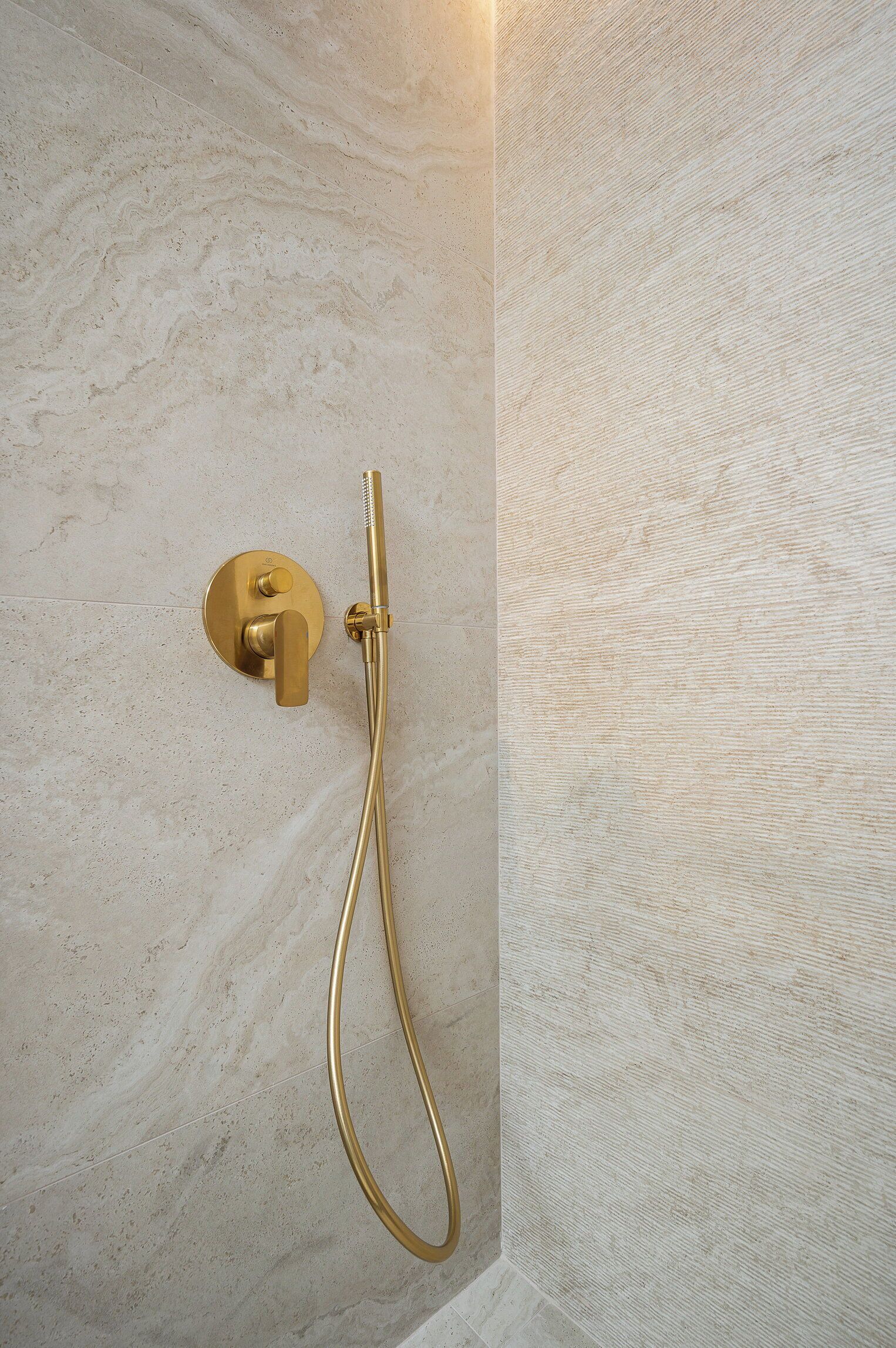 A gold showerhead mounted on a textured wall.