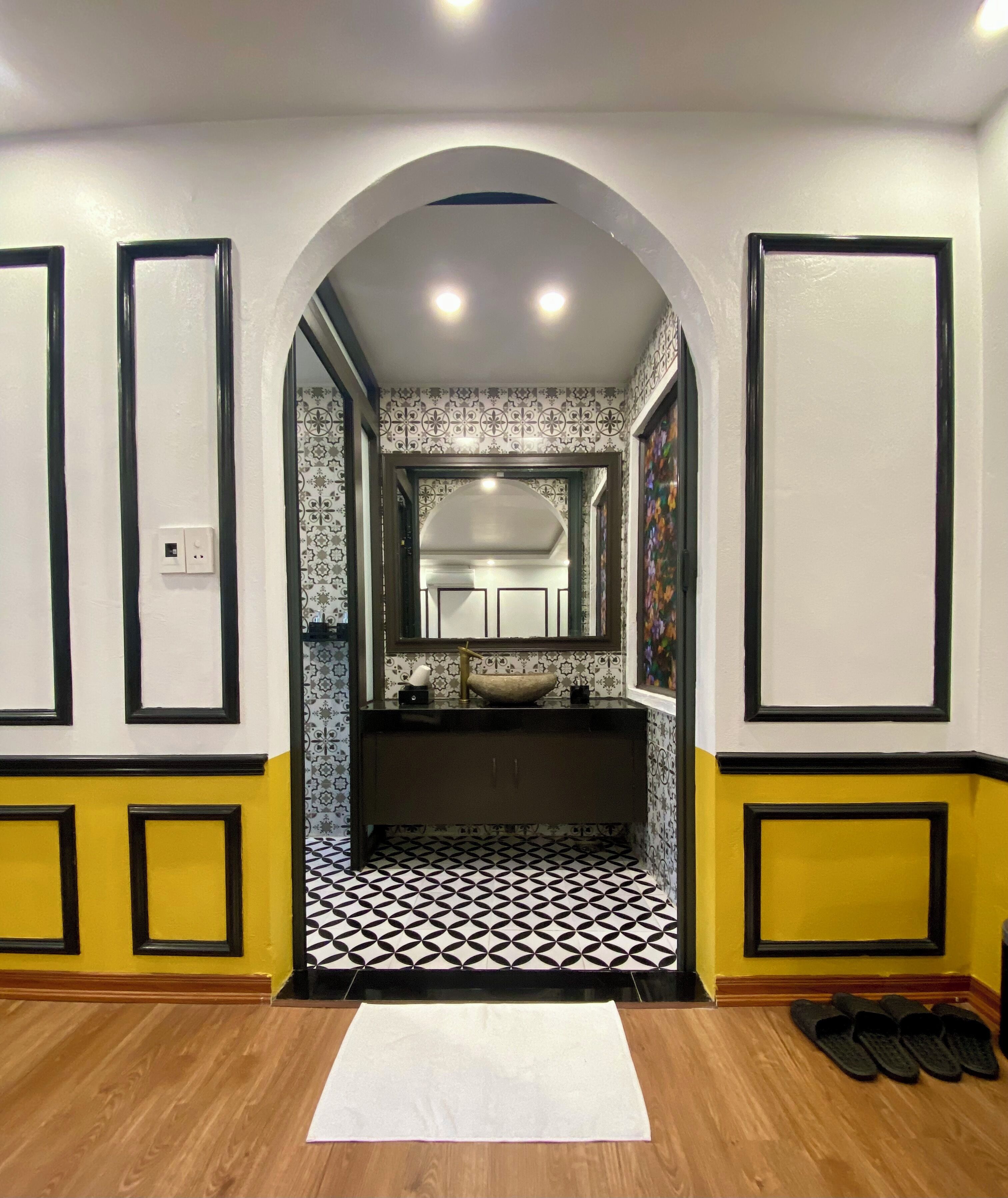Une salle de bain avec un carrelage noir et blanc, un lavabo blanc et un miroir au-dessus.