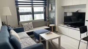 A modern living room with a sofa, a small table, and a TV in the background. - River & Hill view Room (Ansan-si)