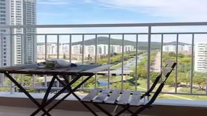 A balcony with a table and chairs, offering a view of a cityscape and greenery. - River & Hill view Room (Ansan-si)