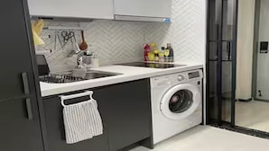 A modern kitchen with a built-in washing machine, a sink, and a herringbone-patterned backsplash. - River & Hill view Room (Ansan-si)