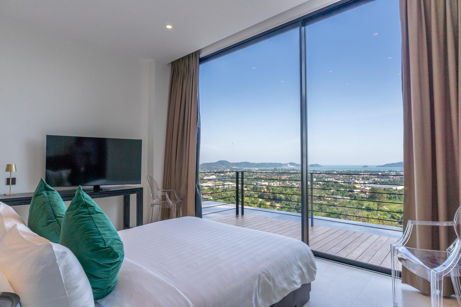 Une chambre moderne avec un grand lit, une télévision et un balcon offrant une vue sur la ville.