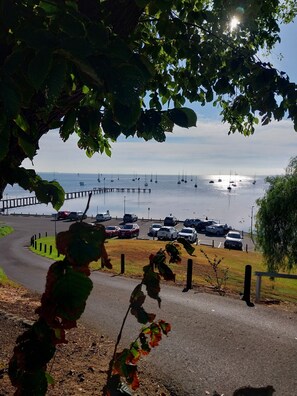 A parking area with cars and a view of the sea with boats.
