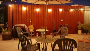 Een buitenterras met een ronde tafel, vier stoelen en een grote parasol.