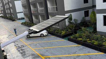 Een modern meerlaags woongebouw met balkons, een parkeerplaats met gele markeringen en een zonnepaneel.