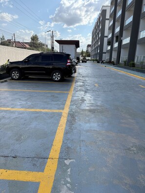A parking lot with a black SUV parked on the left. - Modern Airport Studio Near JKIA, SGR, Nairobi Expy (Syokimau)