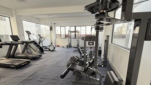 Un gimnasio con cintas de correr, máquinas de pesas y una banca.