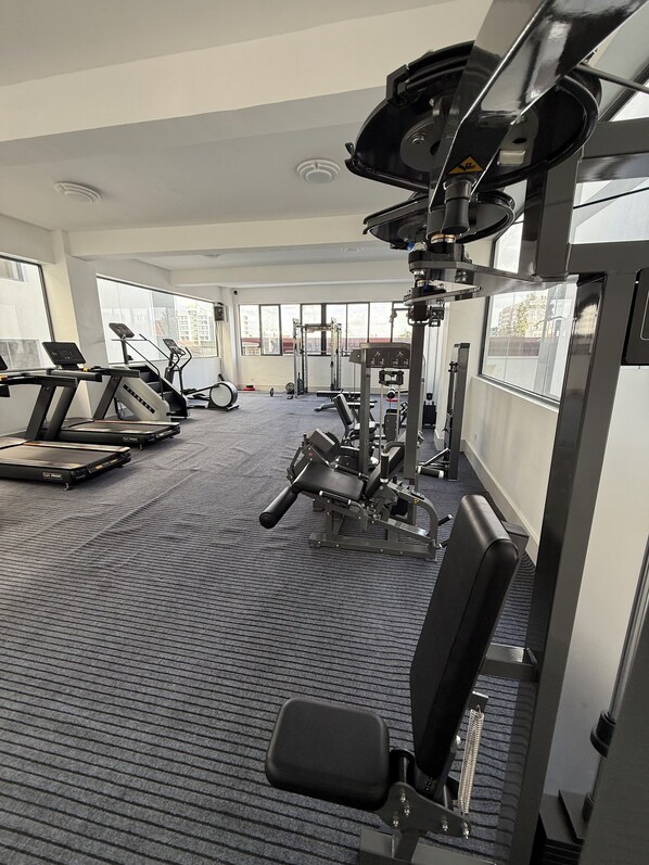 A gym with treadmills, weight machines, and a bench.